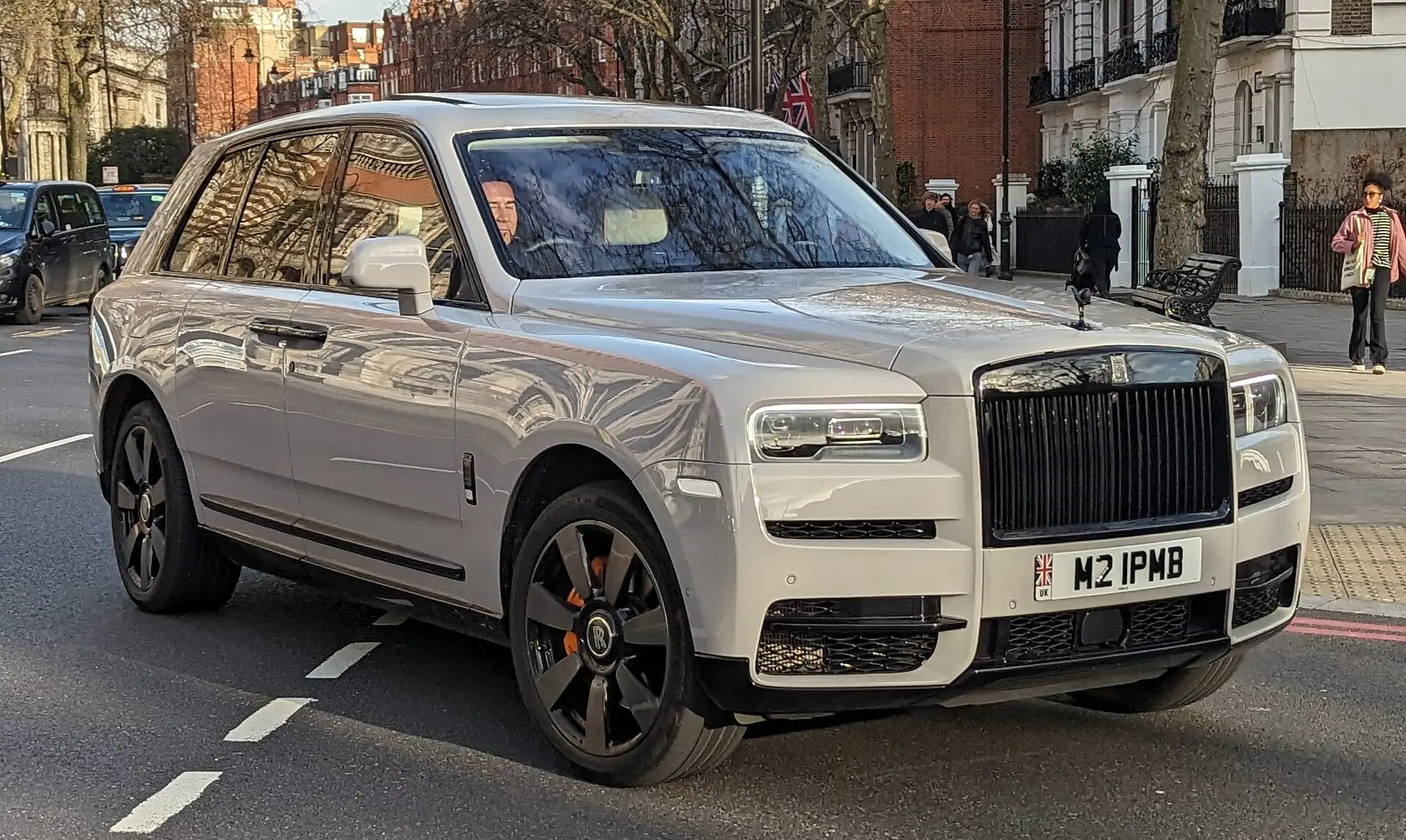 Rolls-Royce Cullinan berwarna krem terparkir di jalan kota