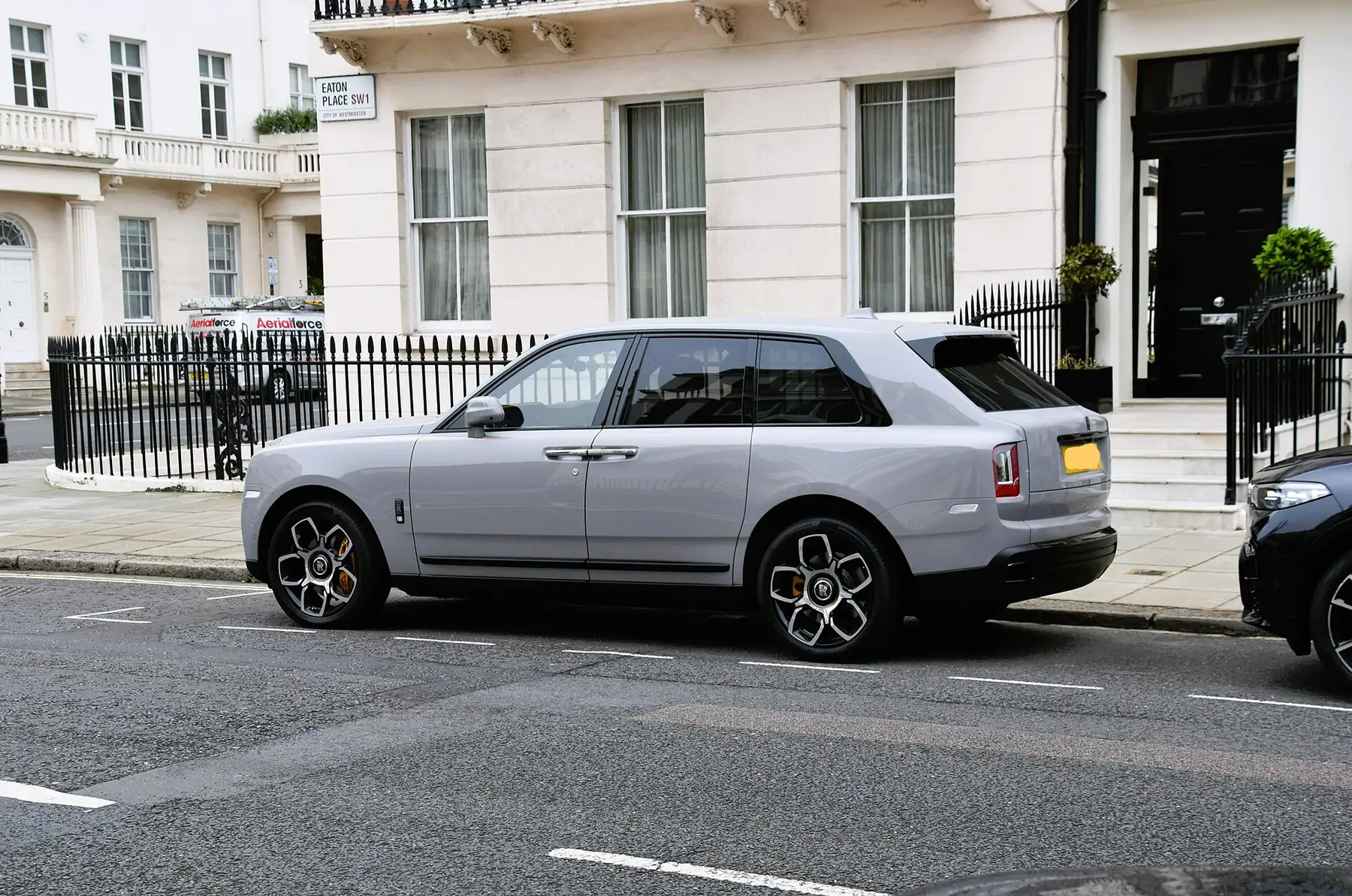 Tampak belakang serong Rolls-Royce Cullinan berwarna putih di tepi jalan