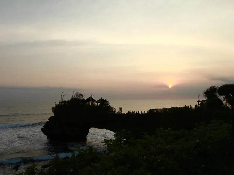 Siluet Pura Tanah Lot di tepi laut Bali saat matahari terbenam