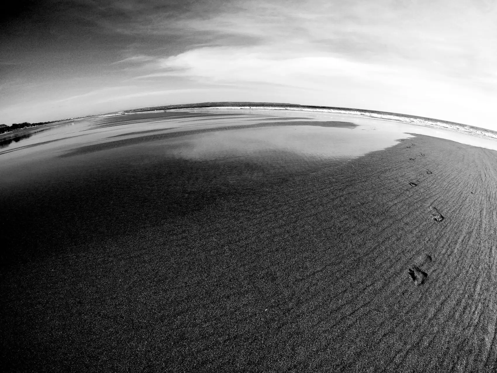Jejak kaki di pasir Pantai Seminyak, foto hitam putih