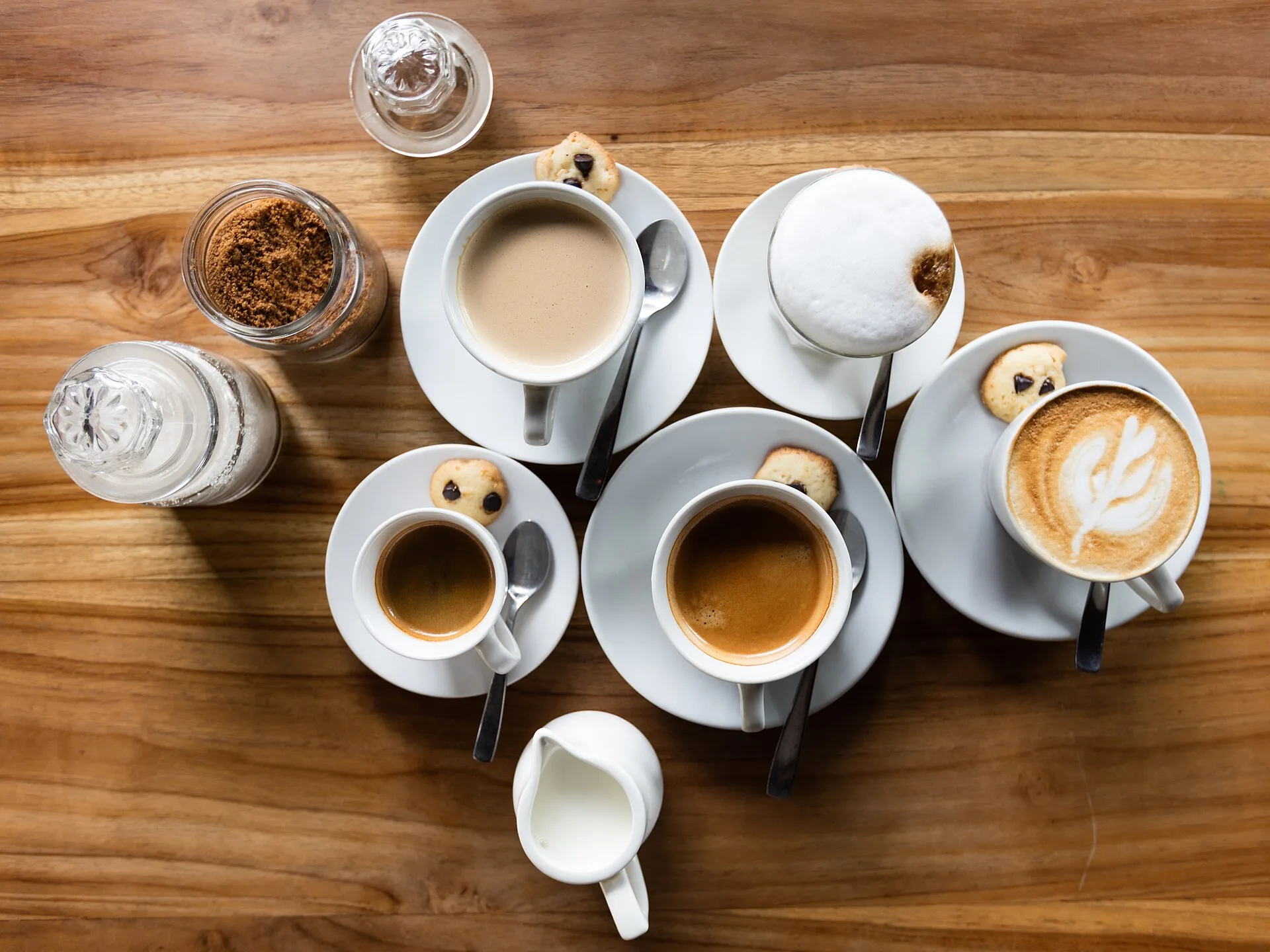 Beberapa cangkir kopi di atas meja kayu di sebuah kedai di Canggu